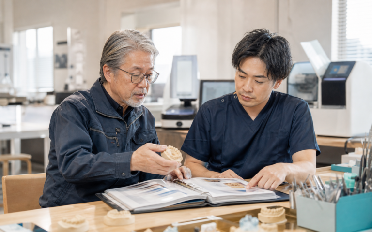 歯科技工所の創業者が若い歯科技工士へ工程と技術を引き継ぐ様子